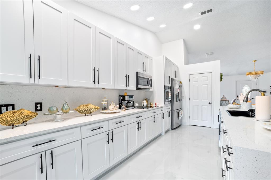 Undisclosed Address Spring Hill, FL 34609 - Photo 12 of 32 a kitchen with kitchen island white cabinets and refrigerator