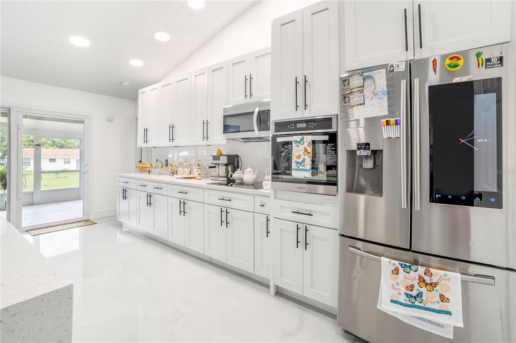 Undisclosed Address Spring Hill, FL 34609 - Photo 13 of 32 a kitchen with stainless steel appliances a refrigerator sink and white cabinets