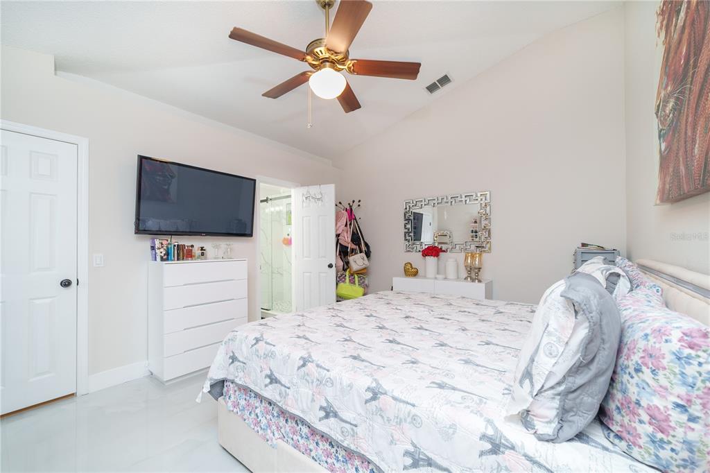 Undisclosed Address Spring Hill, FL 34609 - Photo 16 of 32 a bedroom with a bed and a flat tv screen on dresser