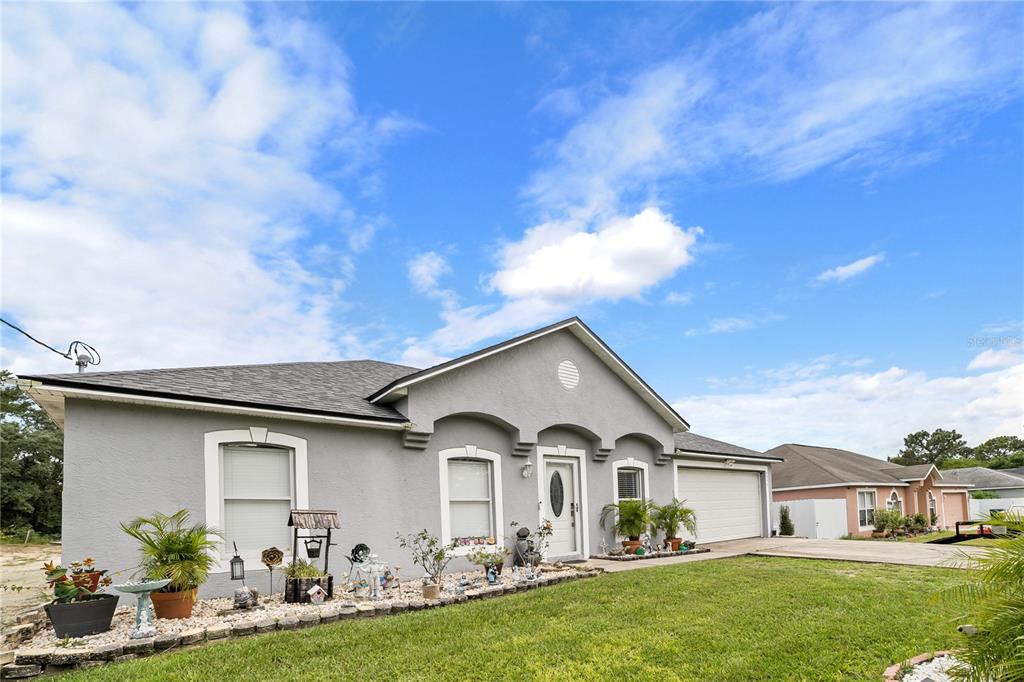 Undisclosed Address Spring Hill, FL 34609 - Photo 3 of 32 a front view of a house with a garden and yard