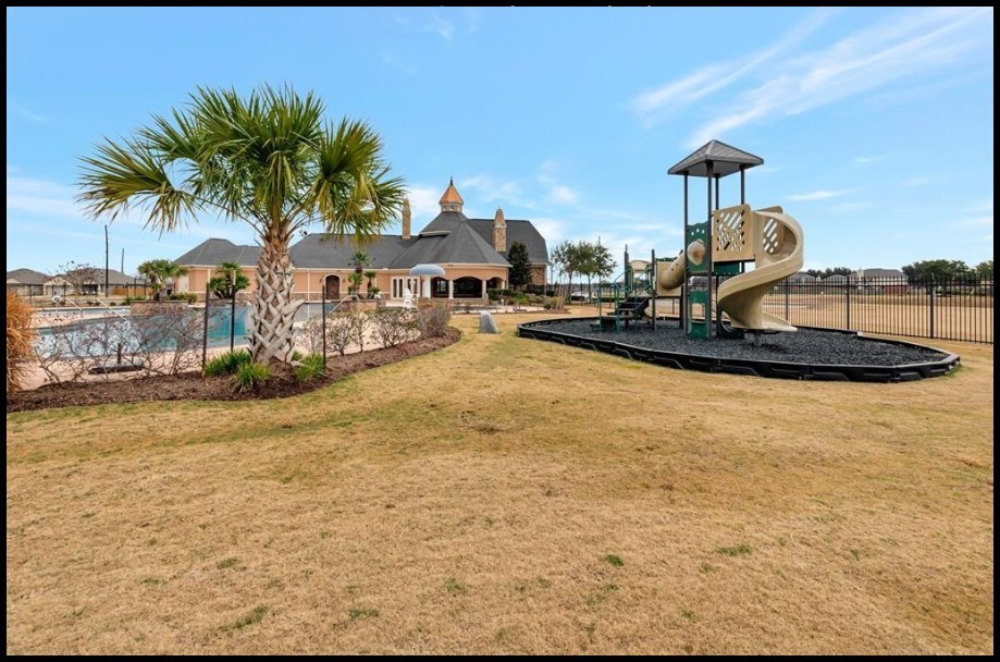 5514 Handlewood Lane Rosenberg, TX 77471 - Photo 4 of 6 This photo showcases a community area featuring a well-maintained playground and a swimming pool, adjacent to a clubhouse with elegant architecture. The landscape includes a palm tree and open grassy space, ideal for families and social gatherings.