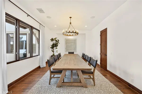 a dining room with wooden floor a chandelier a wooden table and chairs