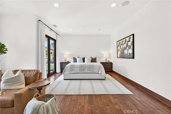 a spacious bedroom with a bed and wooden floor