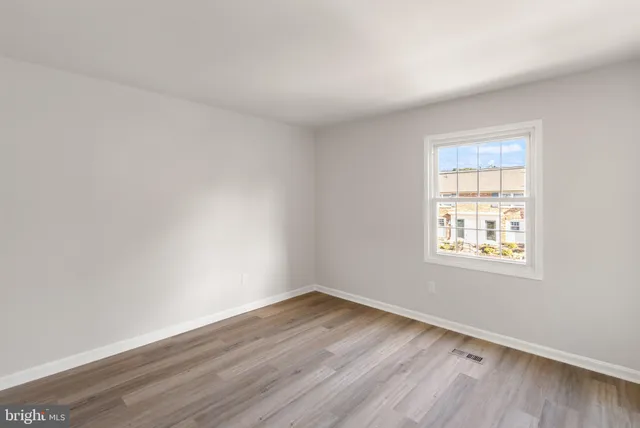 an empty room with wooden floor and window