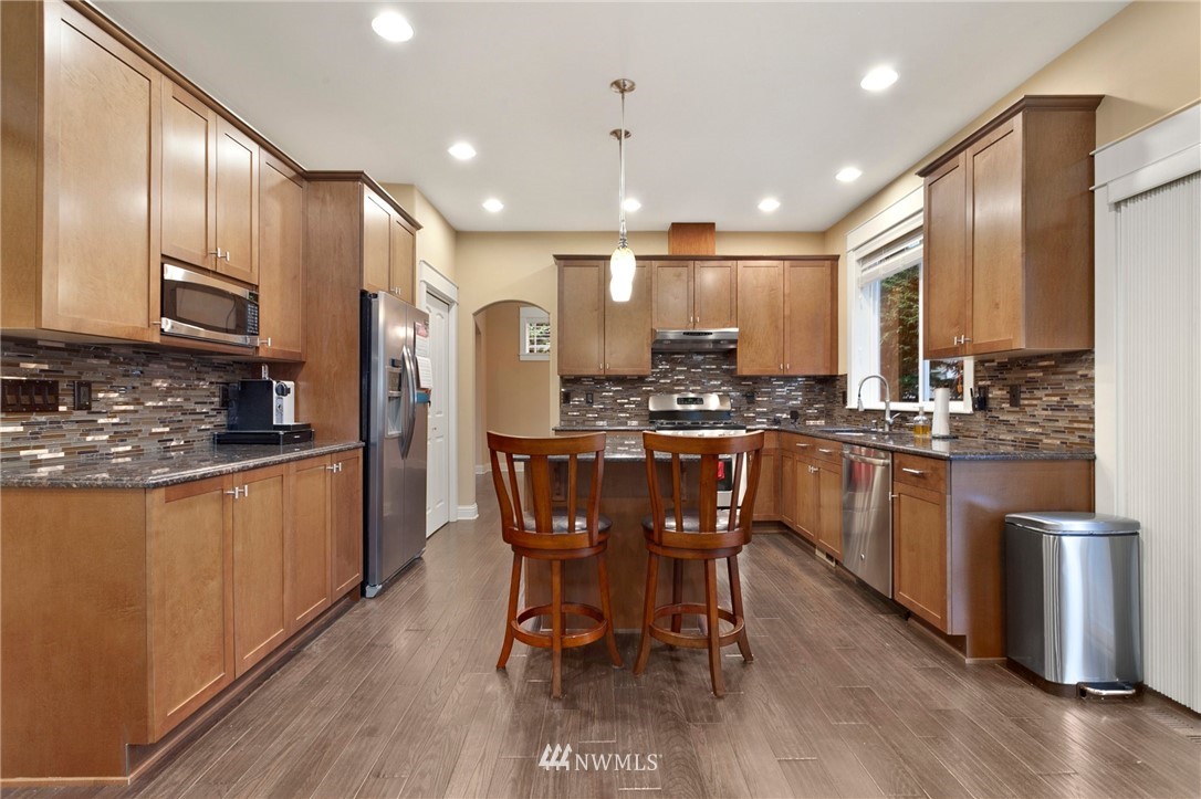 32233 Military Road South Federal Way, WA 98001 - Photo 11 of 28 a kitchen with stainless steel appliances kitchen island granite countertop a sink a stove a refrigerator cabinets and chairs