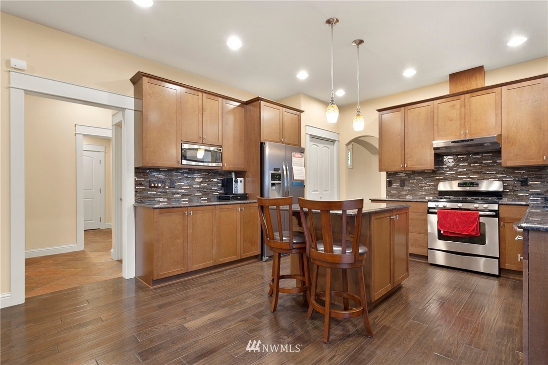 32233 Military Road South Federal Way, WA 98001 - Photo 10 of 28 a kitchen with stainless steel appliances kitchen island granite countertop a stove a refrigerator and a wooden cabinets