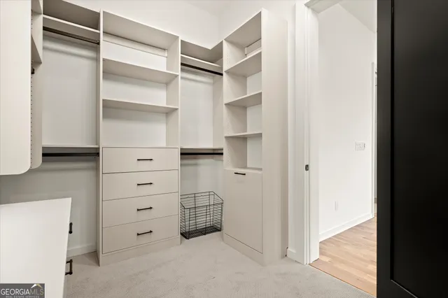 a view of a hallway with wooden floor and a bathroom