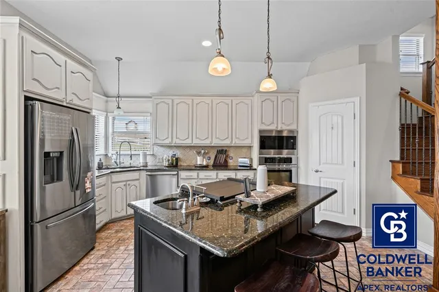 a kitchen with stainless steel appliances granite countertop a sink refrigerator and cabinets