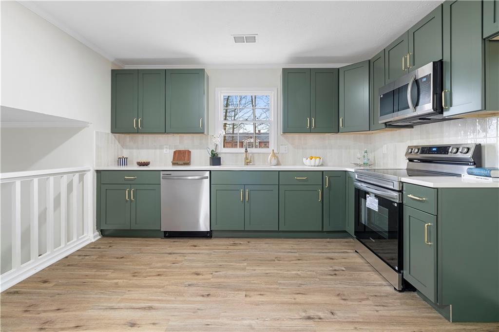 3905 Hunters Chase Southwest Conyers, GA 30094 - Photo 9 of 29 a kitchen with stainless steel appliances granite countertop a sink a stove top oven and wooden floors