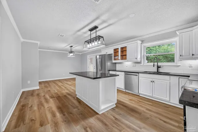 a kitchen with stainless steel appliances granite countertop a sink dishwasher a stove and a dining table with wooden floor