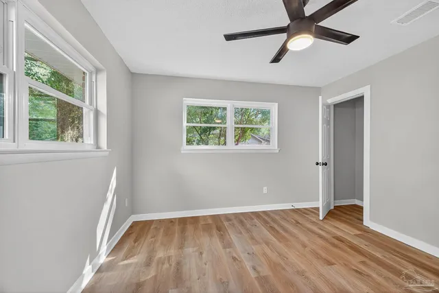 a view of empty room with wooden floor and fan