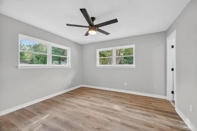 a view of empty room with wooden floor and fan