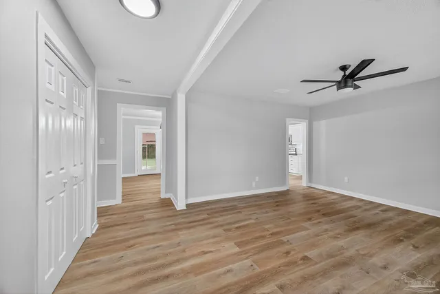 a view of a hallway with wooden floor and a ceiling fan