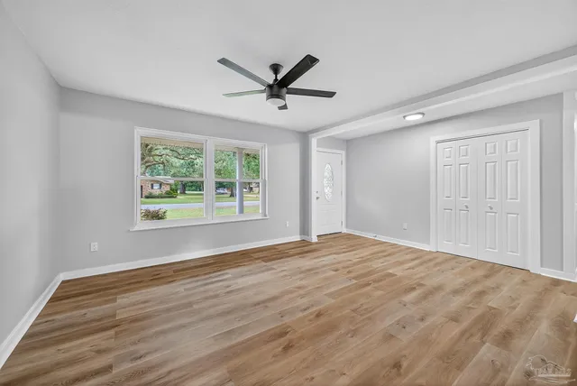 a view of empty room with wooden floor and fan