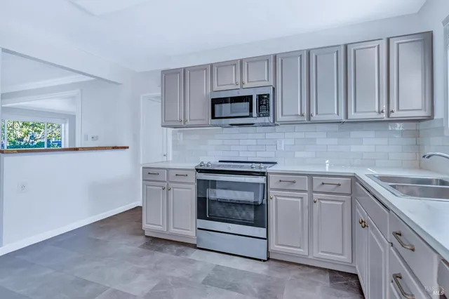 a kitchen with white cabinets and stainless steel appliances