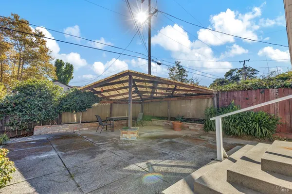 a view of a patio with a table and chairs under an umbrella with wooden fence