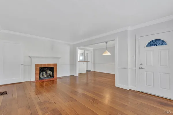 an empty room with wooden floor fireplace and windows
