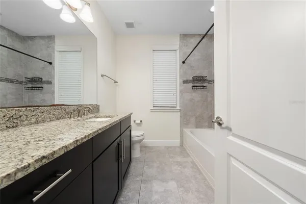 a bathroom with a granite countertop sink a toilet and bathtub