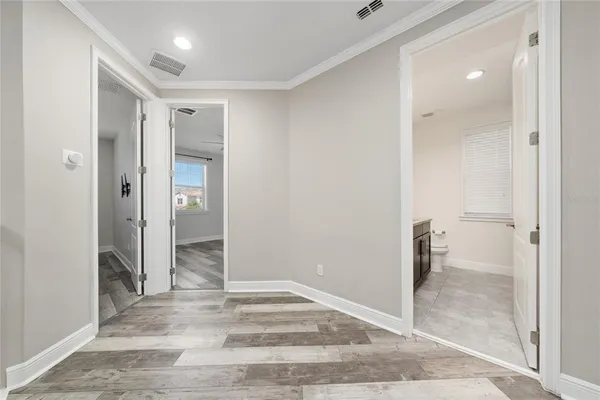 a view of a hallway with wooden floor and a bathroom