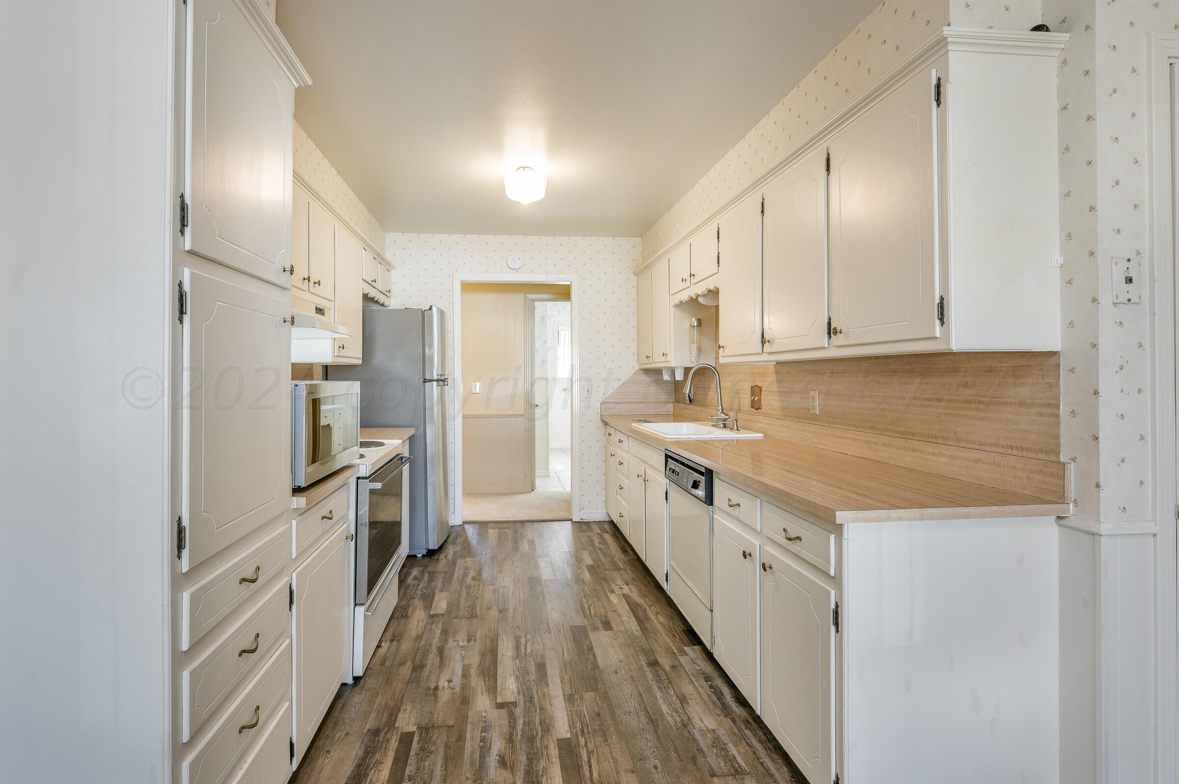 6113 Elmhurst Road Amarillo, TX 79106 - Photo 5 of 28 a kitchen with cabinets and wooden floor