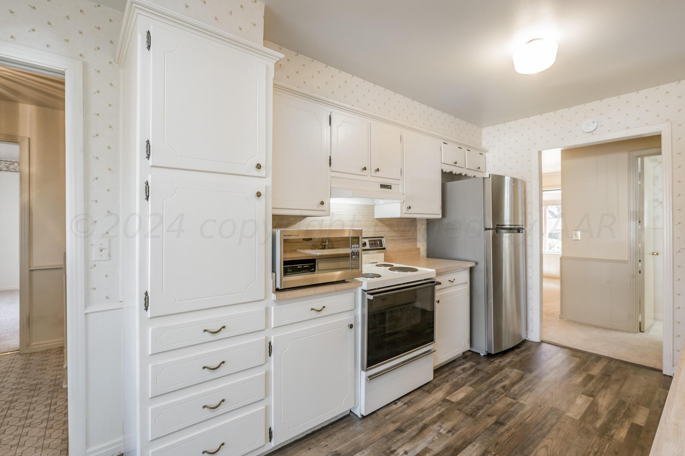 6113 Elmhurst Road Amarillo, TX 79106 - Photo 6 of 28 a kitchen with cabinets stainless steel appliances and wooden floor
