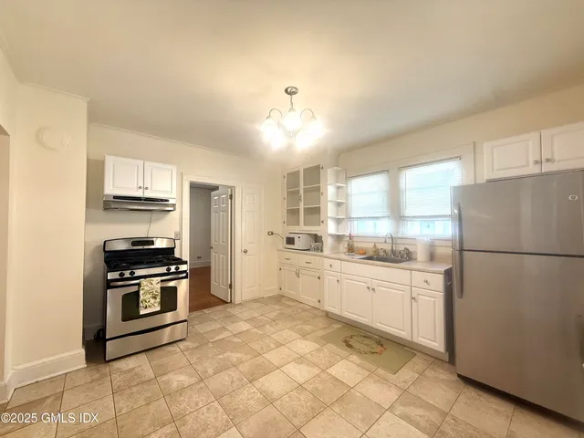 a kitchen with granite countertop a refrigerator stove top oven and sink