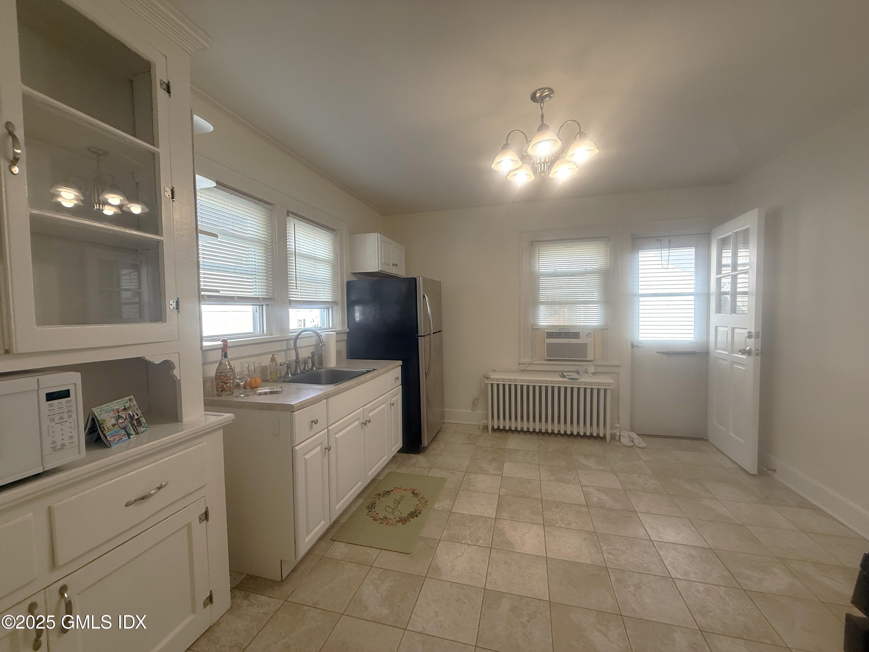 217 River Extension, Unit LOWER LEVEL Cos Cob, CT 06807 - Photo 5 of 16 a kitchen with granite countertop a refrigerator a sink a stove a counter space and cabinets