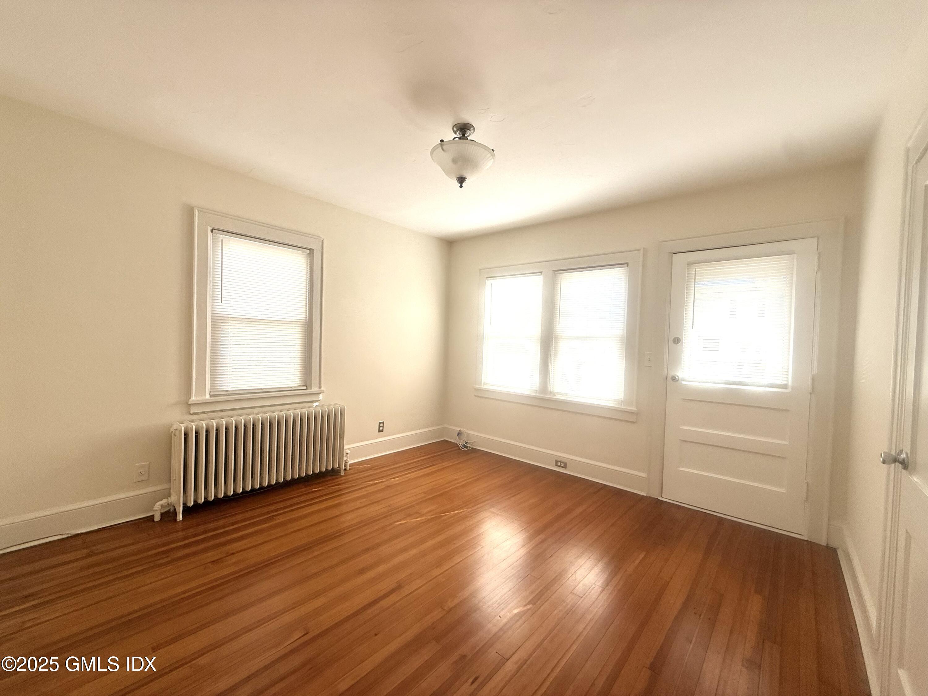 217 River Extension, Unit LOWER LEVEL Cos Cob, CT 06807 - Photo 6 of 16 an empty room with wooden floor and windows