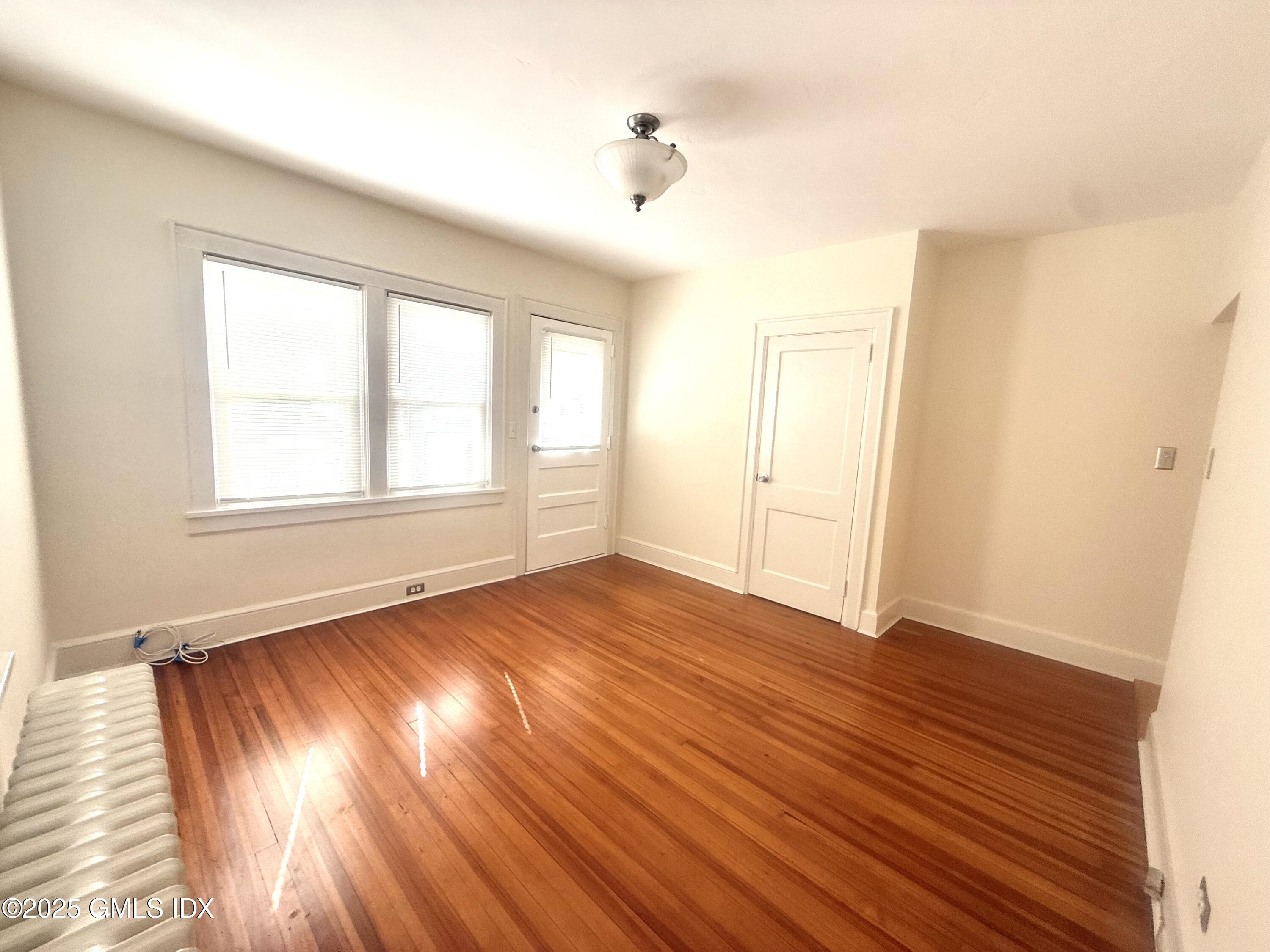 217 River Extension, Unit LOWER LEVEL Cos Cob, CT 06807 - Photo 7 of 16 an empty room with wooden floor and windows