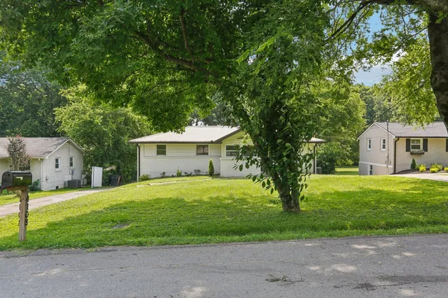 a view of a house with a yard and large tree