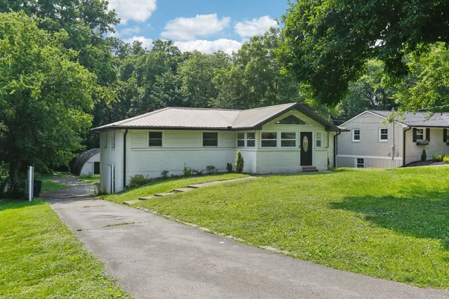 a view of a house with a big yard and large trees