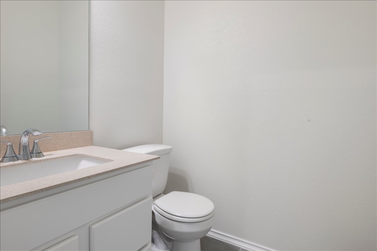 18501 Spotted Eagle Lane Elgin, TX 78621 - Photo 37 of 40 A well-appointed powder room featuring a modern vanity with integrated sink and a sleek toilet.