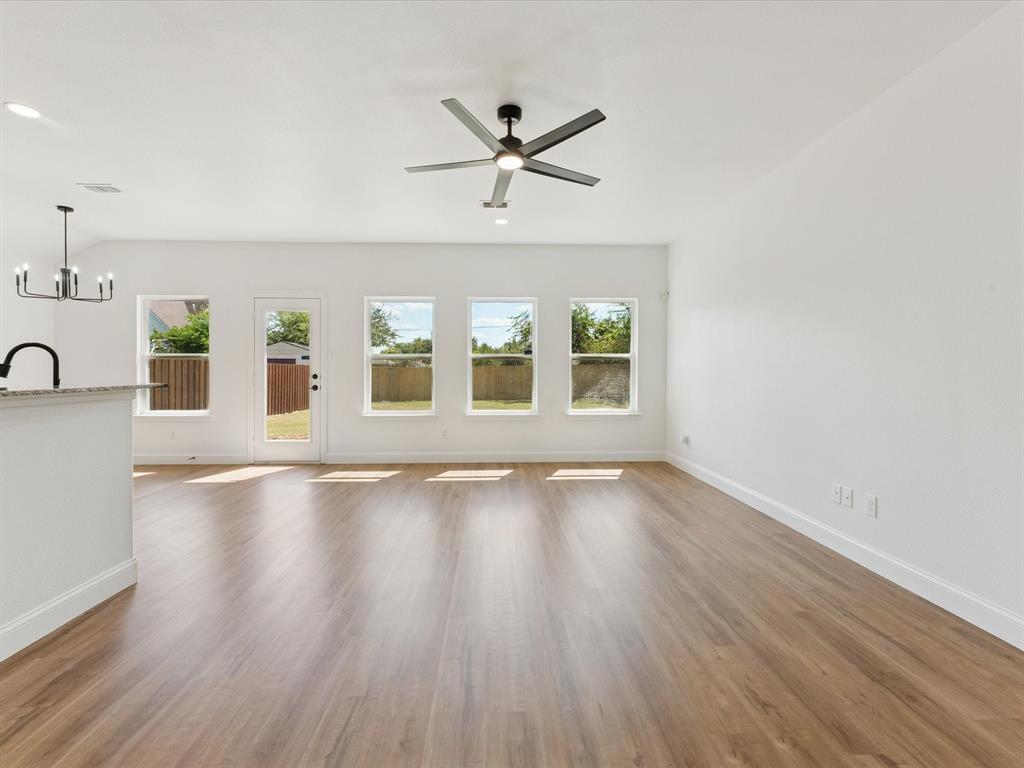 810 Ranch Road Dallas, TX 75253 - Photo 12 of 28 Unfurnished living room featuring light wood-style floors, a chandelier, and ceiling fan