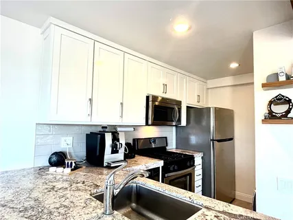 a living room with stainless steel appliances granite countertop a hardwood floor sink and stove