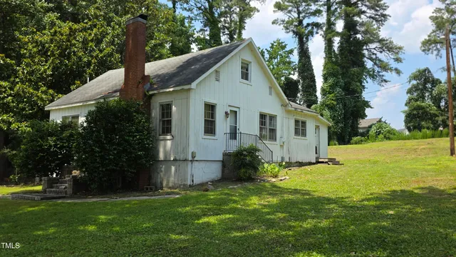 a view of a yard in front of a house with plants and large tree