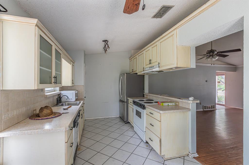 6504 Johnnie Street Watauga, TX 76148 - Photo 5 of 23 Kitchen featuring cream-colored cabinetry, light-toned countertops, and a tiled backsplash