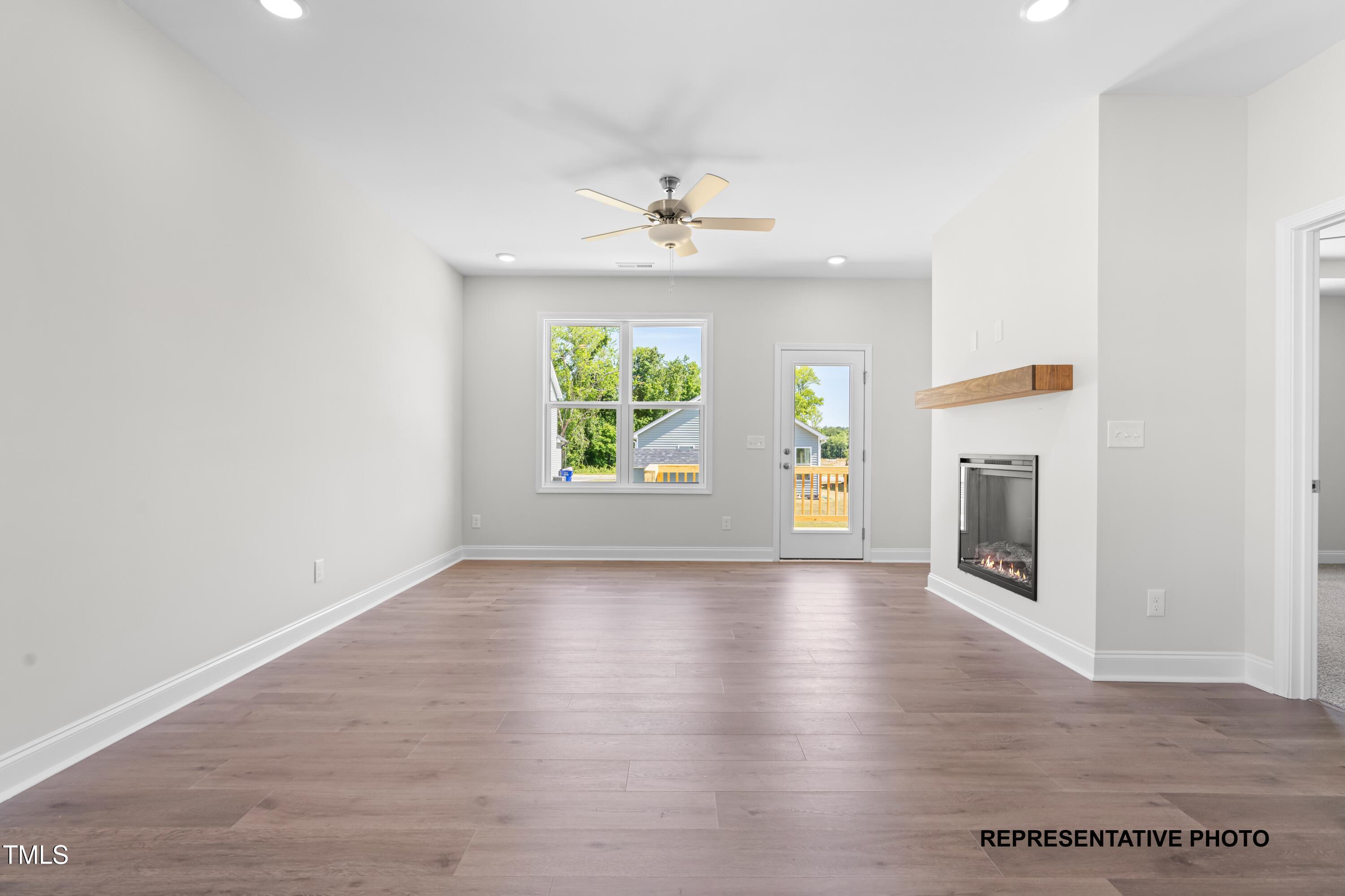 378 Bluejay Street Clayton, NC 27520 - Photo 5 of 13 an empty room with wooden floor a ceiling fan and a window