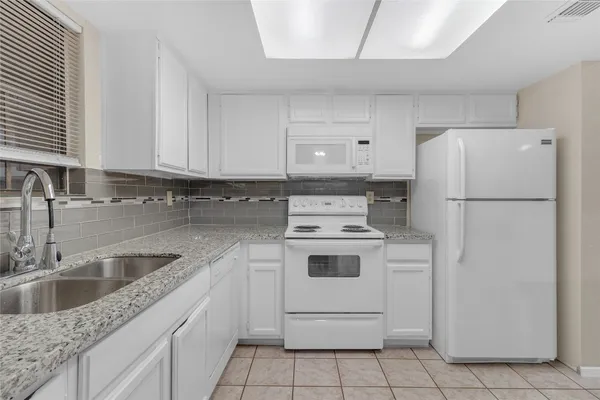 a kitchen with a white stove refrigerator and cabinets