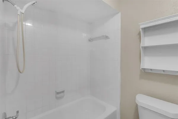 a white bath tub sitting next to a white toilet and vanity
