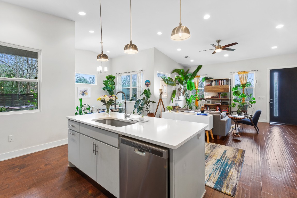 3101 Sunnylawn Circle, Unit B Austin, TX 78723 - Photo 27 of 28 Kitchen with stainless steel dishwasher, hanging light fixtures, open floor plan, dark wood finished floors, and a center island with sink