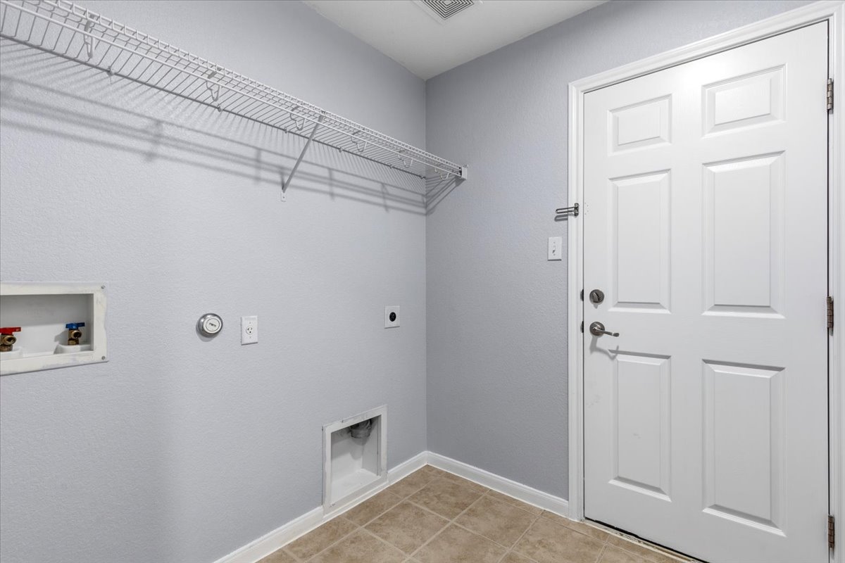 17812 Masi Loop Pflugerville, TX 78660 - Photo 31 of 38 Dedicated laundry area featuring a white wire shelving unit, appliance hookups, and neutral-toned floor tile