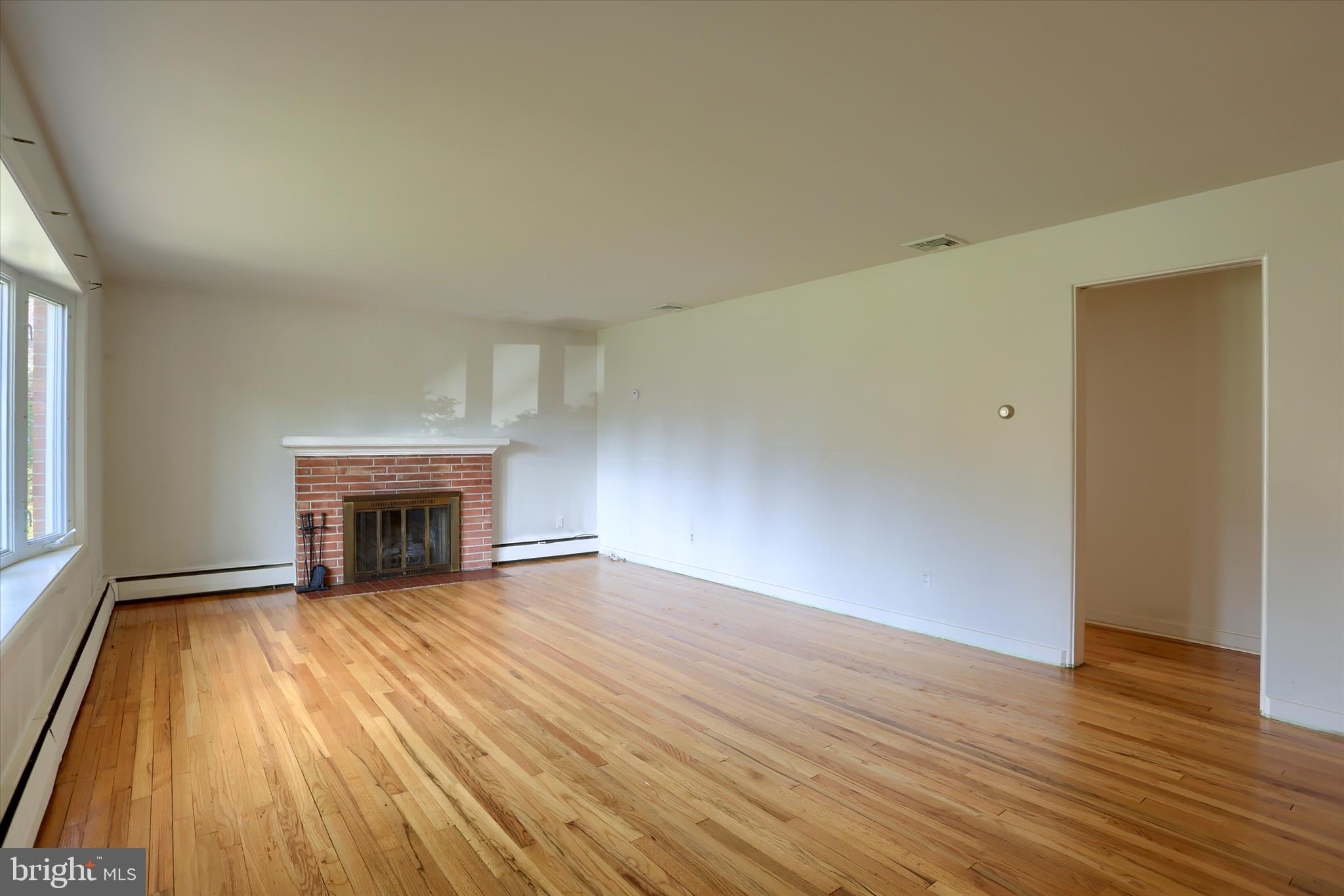 3802 Darby Road Harrisburg, PA 17109 - Photo 4 of 33 an empty room with wooden floor fireplace and windows