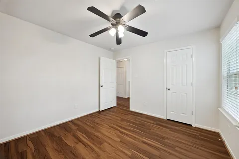 a view of empty room with wooden floor and fan