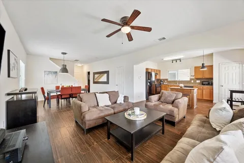 a living room with furniture kitchen view and a wooden floor