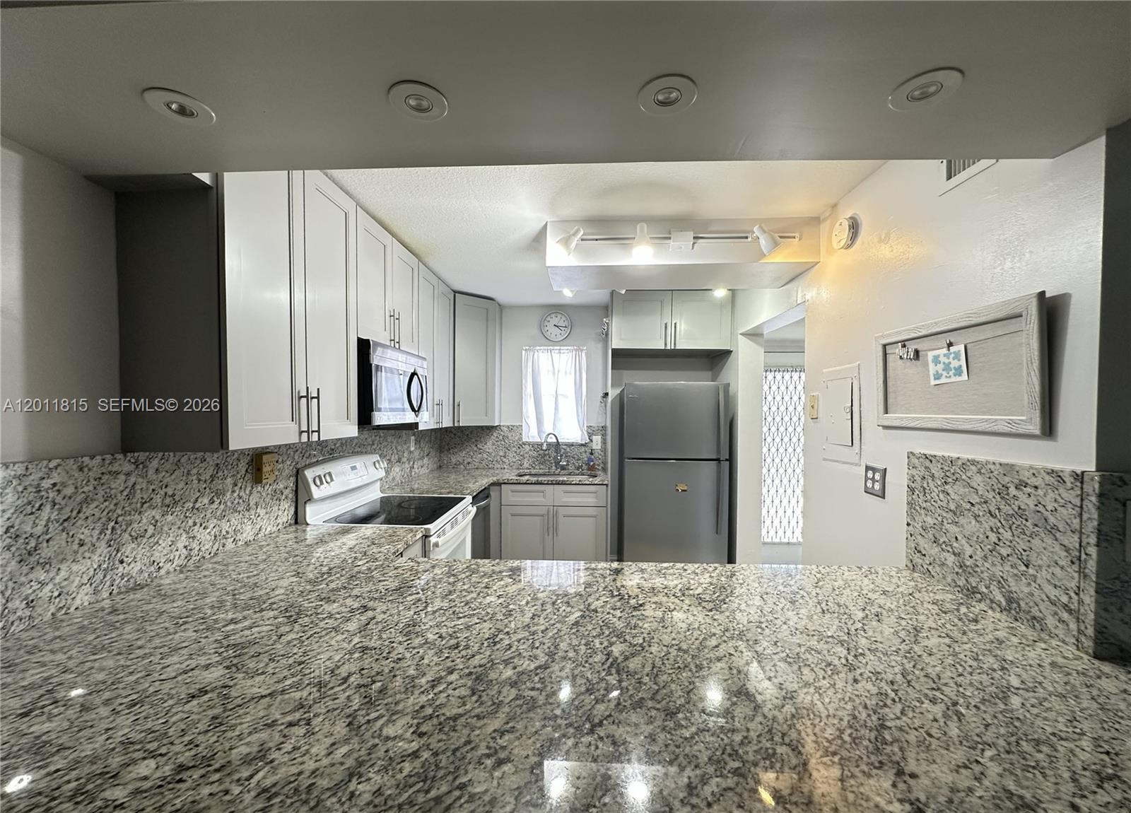 9370 Southwest 8th Street, Unit 107 Boca Raton, FL 33428 - Photo 11 of 17 a kitchen with stainless steel appliances kitchen island granite countertop a refrigerator and a sink