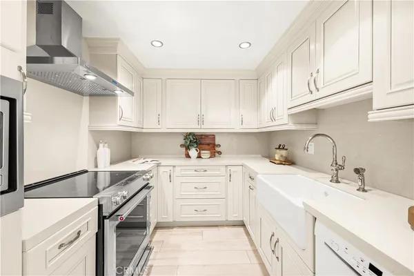 a kitchen with a sink dishwasher and white cabinets with wooden floor