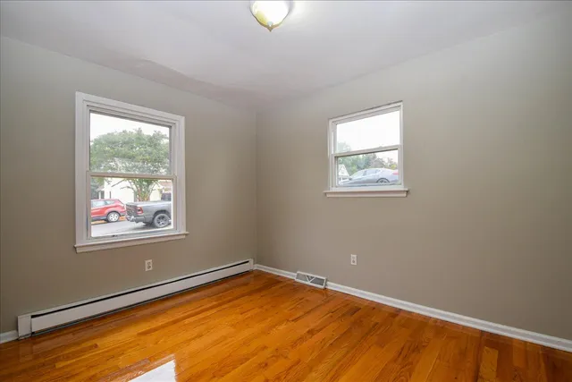a view of an empty room with wooden floor and a window