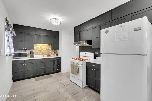 a kitchen with stainless steel appliances granite countertop a refrigerator a sink a stove and a refrigerator