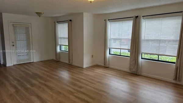 an empty room with wooden floor and windows