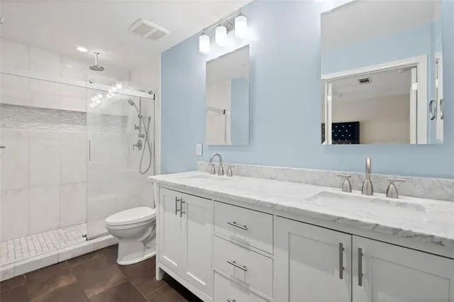 a bathroom with a double vanity sink toilet and shower